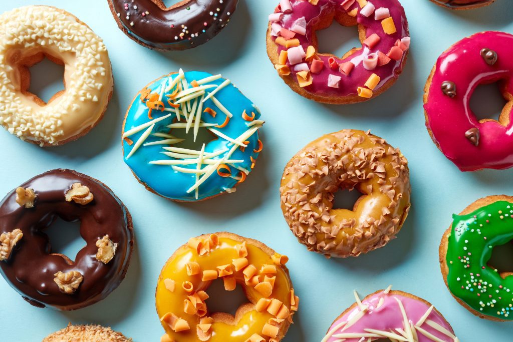 Various colorful donuts on blue background, top view