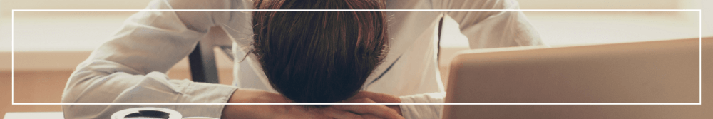 woman with headache at work with head in her hands on desk 